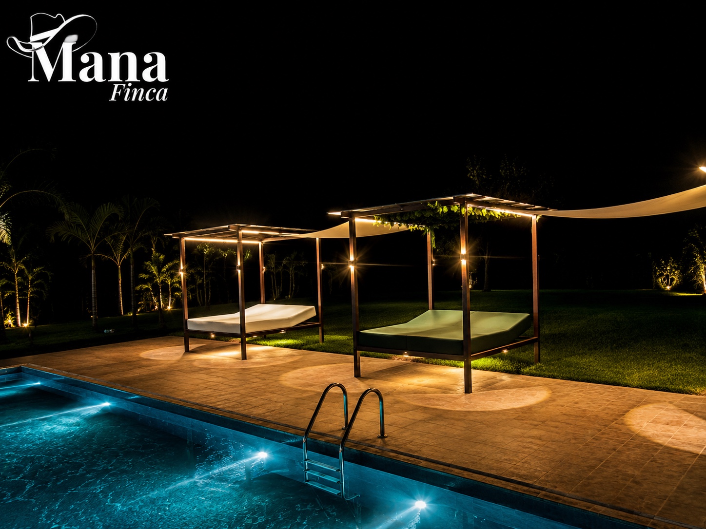 Camas de descanso junto a la piscina de Finca Mana iluminadas de noche