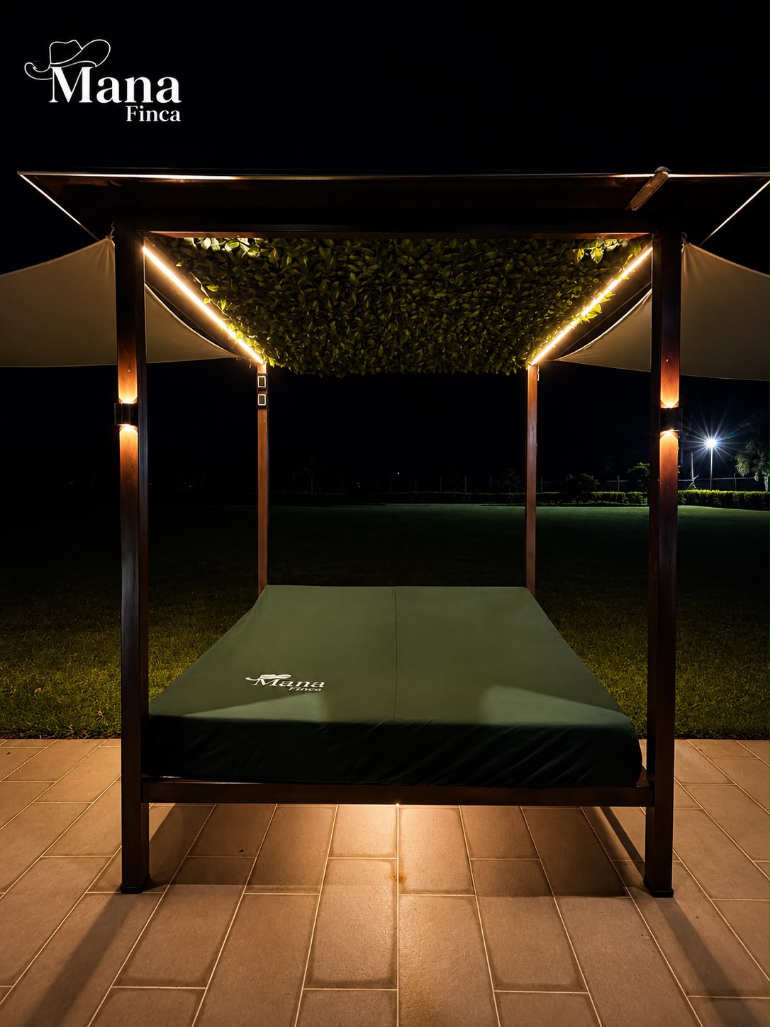Cama de descanso con techo verde y luces cálidas frente al jardín